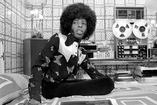 Sly Stone listens to a reel-to-reel tape deck